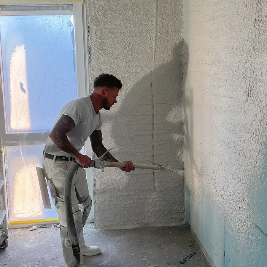 Stukadoor spuit machinaal stucwerk op een wand